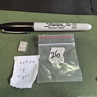 Silver tiger bar beside Sharpie and zip bag