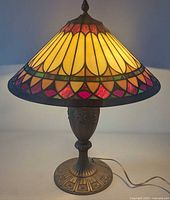 Full view of lamp lit showing stained glass shade and metal base