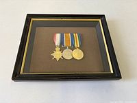 Framed display of three WWI medals in shadow box