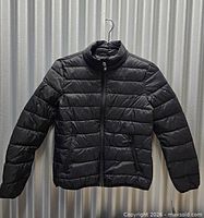 Full front view of black Starter puffer jacket on hanger