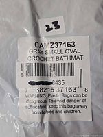 Sealed package labeled CAMZ37163 Gray Small Oval Crochet Bath Mat with barcode