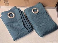 Pair of folded teal grommet curtain panels
