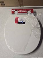 Sealed white toilet seat in plastic wrap with Mainstays header card