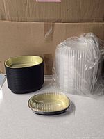 Stack of clear lids next to nested black/gold aluminum bowls from the case