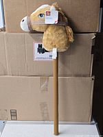 Full view of Play Day hobby horse on stick leaning against boxes