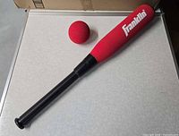 Full view of red foam bat with ball