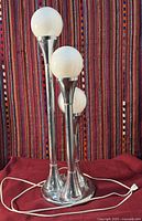 Front view of one chrome triple globe lamp showing base, stems, globes and cord