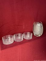 Asteroid vase and three Flora bowls grouped on red background