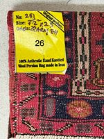 Close-up of corner showing tag indicating size 7'2" x 2'5", hand knotted wool Persian rug made in Iran