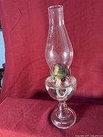Front view of clear glass oil lamp showing chimney, burner and pedestal base