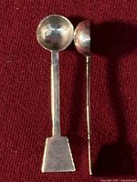Two sterling spoons front view showing bowl shapes and finials