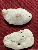 Front view of both jade pendants on red fabric