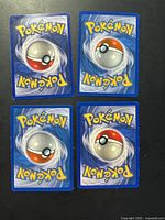 Backs of four Pokémon cards showing standard Poké Ball design
