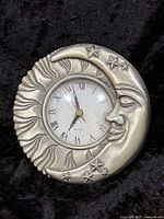 Front view of silver-tone moon and sun clock showing full design and dial