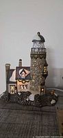 Front view of porcelain lighthouse and cottage showing lighted windows