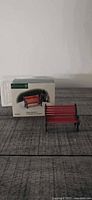 Red miniature bench and original Department 56 box on tabletop