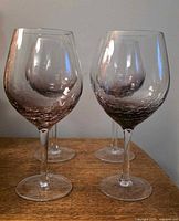 Set of four crackle ombre red wine goblets on wooden surface