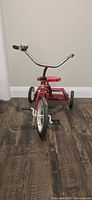 Full view of red Huffy tricycle showing frame, wheels, handlebar