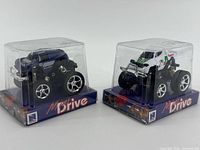 Front view of both boxed mini monster trucks