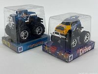 Front view of both sealed NewRay mini trucks in display cases