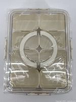 Top view showing six compartments beneath clear lid with circular center divider, shrink wrap visible
