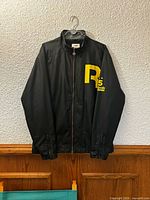 Front view of black Reebok jacket with yellow R graphic