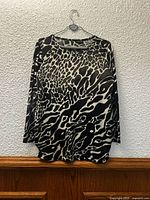 Front view of black and white cheetah print long sleeve top on hanger