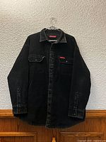Full front view of black Dickies corduroy overshirt on hanger