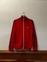 Front view of red Fred Perry track jacket on hanger