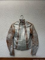 Front view of metallic silver and tan leather moto jacket on hanger