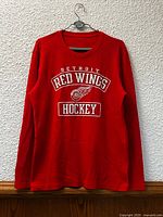Front view of red Detroit Red Wings thermal shirt hanging