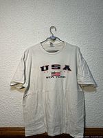 Full view of off-white USA graphic T-shirt on hanger