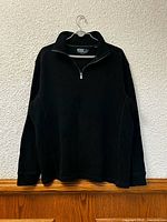Front view of black quarter-zip sweater on hanger
