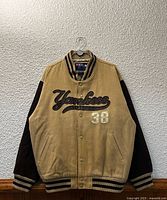 Front view of tan and brown Yankees varsity jacket on hanger