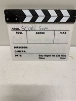 Front of plastic clapperboard showing printed fields and marker writing