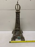 Full view of metal Eiffel Tower sculpture with tape measure indicating height