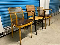 Front angled view of all three chairs showing frames, cane, and leather pads