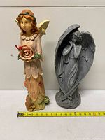Both resin angel figurines beside tape measure
