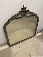 Full front view of mirror showing frame, finial and glass