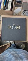 Front cover showing ROM logo on black cloth board