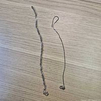 Two sterling silver bracelets laid out showing chain styles and clasps