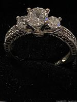 side profile showing three-stone prong setting and band detailing