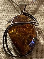 Front view of cognac amber pendant in silver wire bezel on chain
