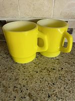 Front view of both yellow milk glass mugs on countertop