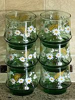 Six stacked light green tumblers with daisy and gold wheat design