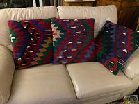 Three multicolor kilim-style pillows on beige sofa