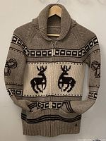 Front view of lambswool cardigan on hanger showing deer motif, zipper and pockets