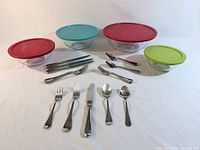 All four Pyrex bowls with lids and full flatware set displayed