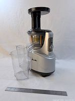 Front view of Breville juicer with both containers and 12-inch ruler for scale