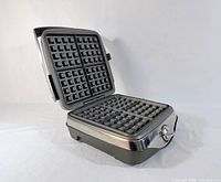 Waffle maker open showing nonstick 4-square plates